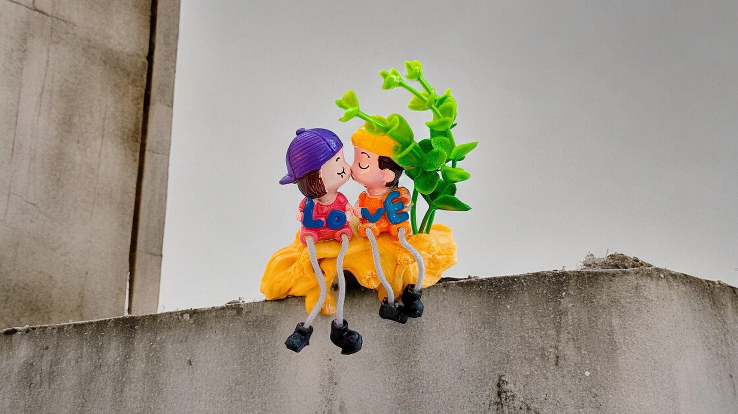 Cute Kissing Couple with Hanging Legs Sitting on the Wall