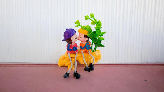 Cute Kissing Couple with Hanging Legs Sitting on the Wall